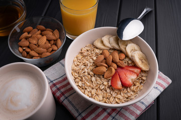 Oatmeal cereal. Natural healthy food. Organic meal. Vegetarian nutrition. Fresh juice, honey, nut, strawberry, banana, coffee on black background
