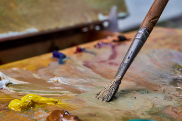 creative image, artist's palette with oil paints and brushes, close-up, old wooden palette, paints of different colors, close-up of the artist's brush