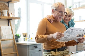 Smiling man engaging in reading while his spouse embracing him