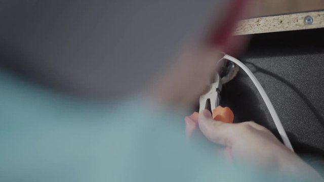 Close up of the craftman electrician checking wires in the furniture. Failure to comply with safety standards. Concept of hand manufacturing. Craftman works in a workshop