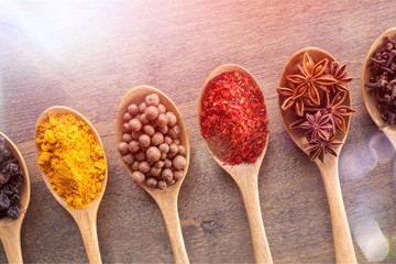 Various colorful spices in spoons on wooden table