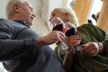 Close-up of spouses keeping glasses of red wine in hands