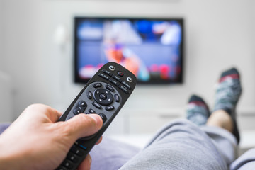 closeup of man relaxed in sofa using changing channel with remote