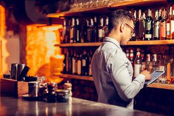 Businessman using tablet while ordering alcohol for bar