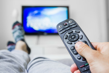 closeup of man relaxed in sofa using changing channel with remote