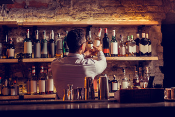 Businessman taking bottle of cognac while standing at his bar stand
