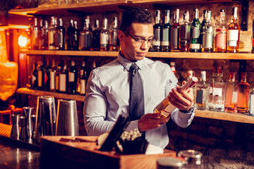Handsome businessman wearing glasses holding bottle of whisky
