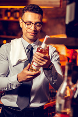 Rich man standing in his bar and holding bottle of alcohol
