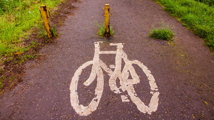 A white bicycle sign on the path at the start of a cycle route.