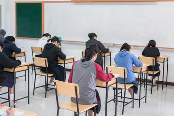 Behind group of asian high school, university student having test exams for taking writing...