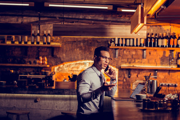Man calling his business partner while working remotely from bar