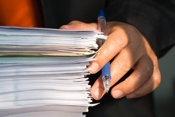Business Documents concept : Employee man hands working in Stacks paper files for searching and...