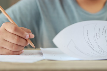 Student hand testing doing test exam with pencil drawing selected choices on answer sheet in school final exams at college or university. Taking multiple choice for assessment in examination classroom