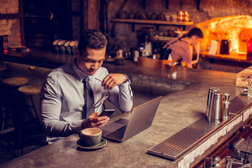 Freelancer reading message on smarpthone sitting in the bar