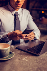 Businessman typing message on phone after drinking coffee