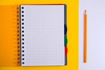 Top view of open spiral blank notebook with pencil on yellow desk background