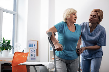 Nice pleasant nurse helping her patients to walk