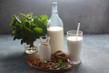 Almond milk in glass bottles with almonds on background. Vegan diary concept. Healthy food and drinks