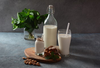 Almond milk in glass bottles with almonds on background. Vegan diary concept. Healthy food and drinks