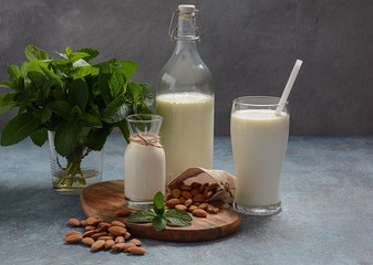 Almond milk in glass bottles with almonds on background. Vegan diary concept. Healthy food and drinks