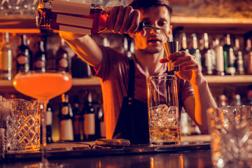 Busy barman making cocktails for clients at night