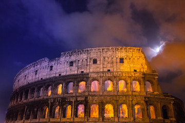 Dettaglio del Colosseo di notte con la luna piena  e finestre infuocate