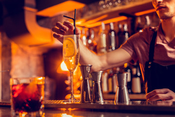 Barman putting straw into glass of cocktail with lemon