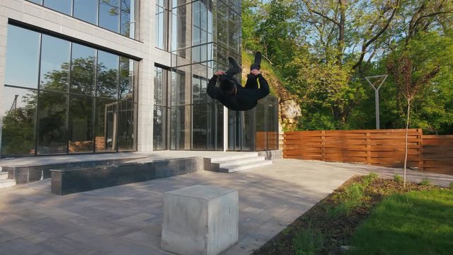 Young man parkour athlete in urban modern city doing extreme tricks, slow motion