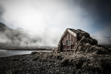 Small wooden house with grass roof in the Iceland fjord. Toned