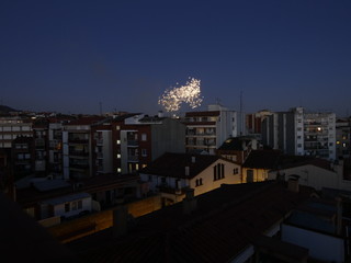 Vista nocturna de un barrio cualquiera de una ciudad cualquiera con fuegos artificiales al fondo