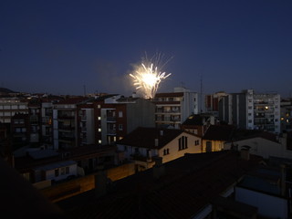 Vista nocturna de un barrio cualquiera de una ciudad cualquiera con fuegos artificiales al fondo