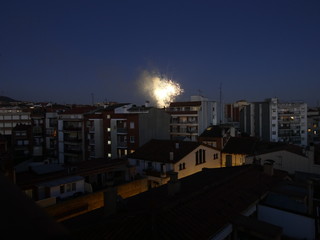 Vista nocturna de un barrio cualquiera de una ciudad cualquiera con fuegos artificiales al fondo