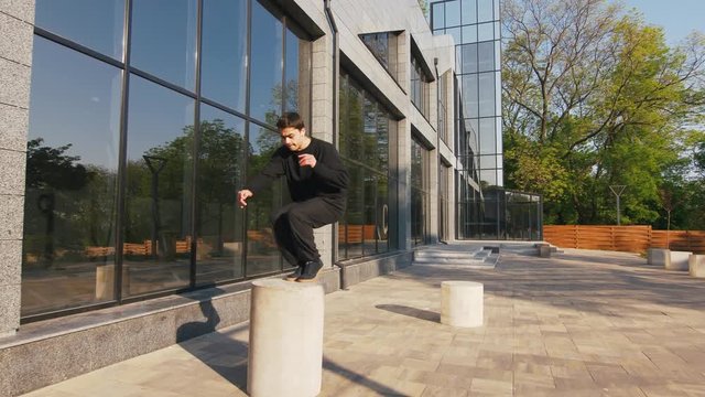 Young man parkour athlete in urban modern city doing extreme tricks, slow motion