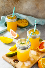 Refreshing summer cocktails made of citrus and mango, cold drink with ice on a stone or slate background. Concept fresh vitamins. Rustic style. Free space for your text.
