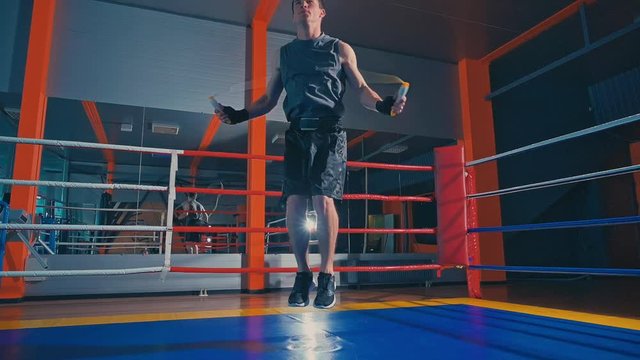 Man fighter skipping at the boxing ring. Young athletic man doing warm-up before exercise. Slow motion
