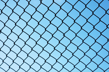 View of blue sky through metal grid. Background of metal mesh