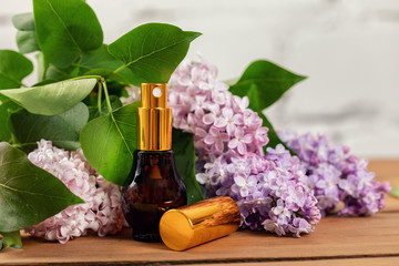 lilac perfume - scent sprayer and blossoms on wooden table