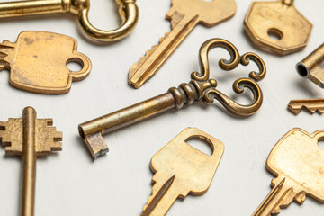 Lot of keys old and new yellow gold color on a white background