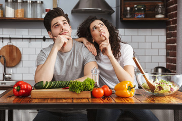 Excited cheerful young couple cooking healthy salad