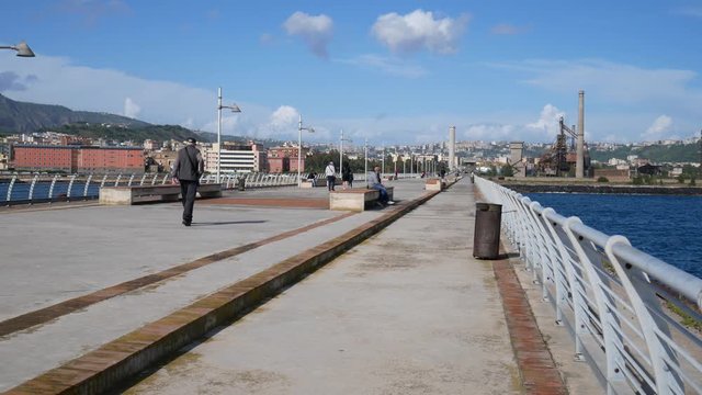 Naples, Campania, Italy - april 24 2019: people walk in a pedestrian area in the middle of the sea , old jetty of the former steelwork of the italsider, a reclaimed area in Bagnoli