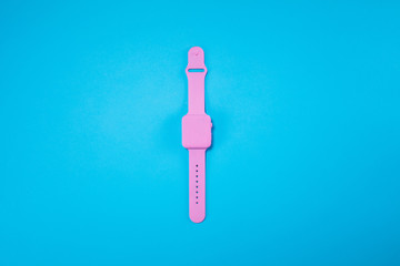 Pink watch lie on pastel blue background. Minimal summer concept.