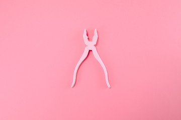 Pink pliers lie on pastel pink background. Minimal summer concept.