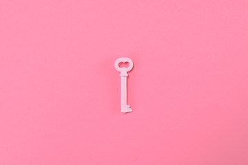 Pink key lie on pastel pik background. Minimal summer concept.