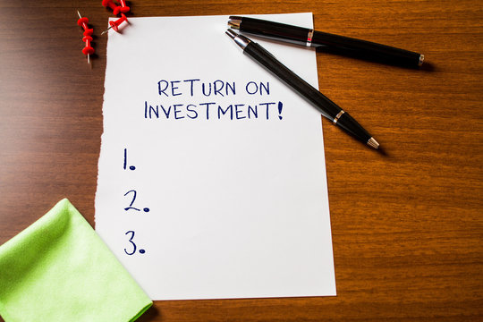 Text sign showing Return On Investment. Business photo showcasing perforanalysisce measure used evaluate efficiency of investment Blank stationary paper wooden table fountain pen cloth rag pins to fix