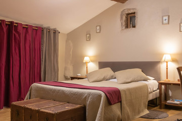 Lit double devant une fenêtre avec de grands rideaux et une tête de lit en tissu et une malle en...