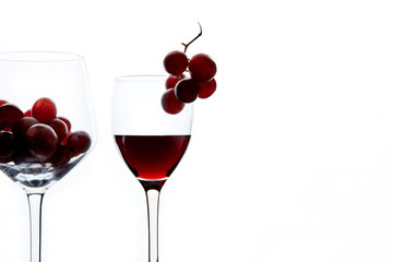 Red grape and wine in crystal glasses on white background