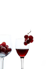 Red grape and wine in crystal glasses on white background