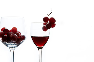 Red grape and wine in crystal glasses on white background