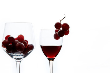 Red grape and wine in crystal glasses on white background