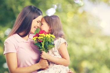 Portrait of happy mother and daughter holding  flowers on natural background